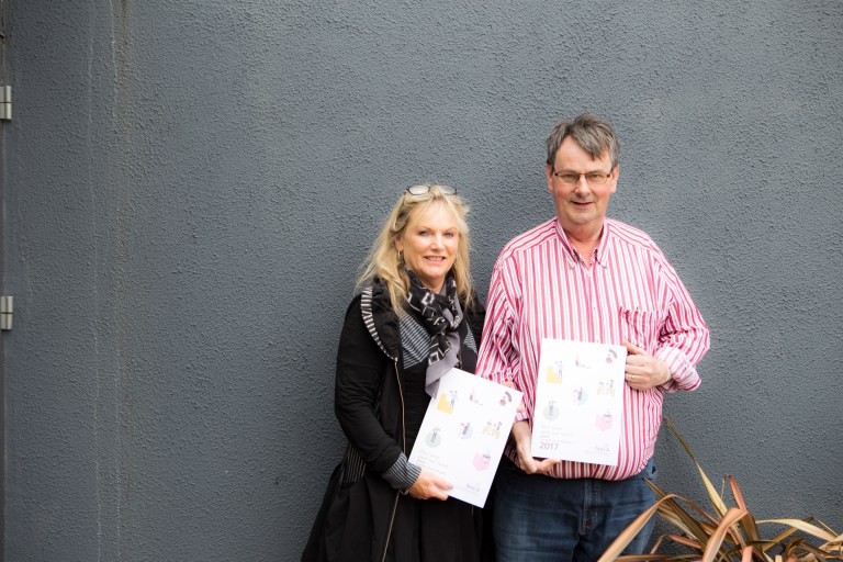 Two parents, holding a piece of paper each